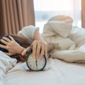 alarm clock and asian woman hand stop time in bed while sleeping, young adult female wake up late in the early morning. Relaxing Royalty Free Stock Photo