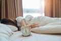 alarm clock and asian woman hand stop time in bed while sleeping, young adult female wake up late in the early morning. Relaxing Royalty Free Stock Photo