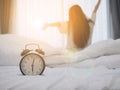 Alarm clock on the bed in bedroom on morning with background of people wake up
