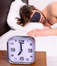 Alarm clock on bedside table man sleepy unshaven bearded face sleep in eye mask background. Healthy sleep tips. Alarm