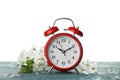 Alarm clock and branch with spring blossoms on wooden table against white background. Time change concept Royalty Free Stock Photo