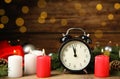 Alarm clock, burning candles and Christmas decor on wooden table, bokeh effect Royalty Free Stock Photo