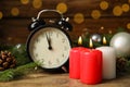 Alarm clock, burning candles and Christmas decor on wooden table, bokeh effect Royalty Free Stock Photo