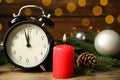 Alarm clock, burning candles and Christmas decor on wooden table, bokeh effect Royalty Free Stock Photo