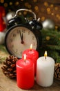 Alarm clock, burning candles and Christmas decor on wooden table, bokeh effect Royalty Free Stock Photo