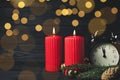 Alarm clock, burning candles and Christmas decor on wooden table, bokeh effect. Space for text Royalty Free Stock Photo