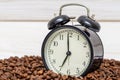 Alarm clock and coffee beans on a white wooden background. Alarm clock standing on the beans of coffee. Coffee time concept Royalty Free Stock Photo