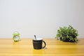 Alarm clock, coffee cup, and potted baby sun rose on home desk