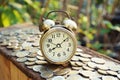 Alarm clock and coin pile on wooden table with blur green garden background, bright morning color tone, finance and business