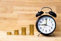 Alarm clock and coins stack on wood table and wooden background, savings money concept. Royalty Free Stock Photo