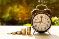 Alarm clock and coins with sunlight in the park Represents the beginning of saving money. Royalty Free Stock Photo