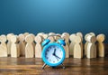 Alarm clock and a crowd of people. Time management. Hourly wages, strict work limits and break time. Planning and forecasting. Royalty Free Stock Photo