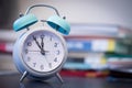 Alarm clock on the desk, books and office stuff in the blurry background, deadlines and todos Royalty Free Stock Photo