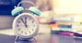 Alarm clock on the desk, books and office stuff in the blurry background, deadlines and todos Royalty Free Stock Photo