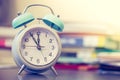 Alarm clock on the desk, books and office stuff in the blurry background, deadlines and todos Royalty Free Stock Photo