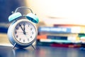 Alarm clock on the desk, books and office stuff in the blurry background, deadlines and todos Royalty Free Stock Photo