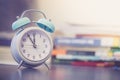 Alarm clock on the desk, books and office stuff in the blurry background, deadlines and todos Royalty Free Stock Photo