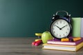 Alarm clock and different stationery on table near green chalkboard, space for text. School time Royalty Free Stock Photo