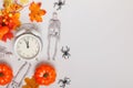 Alarm clock with fallen leaves pumpkins skeletons spiders. Transitional change of autumn time, change of seasons halloween