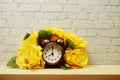 Alarm clock with flower decorative on white brick wall background Royalty Free Stock Photo