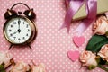 Alarm clock and gift box with roses bouquet with space copy on pink polka dot background Royalty Free Stock Photo