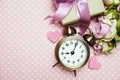 Alarm clock and gift box with roses bouquet with space copy on pink polka dot background Royalty Free Stock Photo