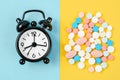 The alarm clock and many drug on a yellow background. Taking medicine at the right time concepts