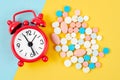 The alarm clock and many drug on a yellow background. Taking medicine at the right time concepts