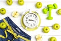 Alarm clock with measure tape, blue womans jeans, green apples a Royalty Free Stock Photo