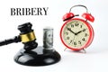 Alarm clock, money banknote and judge gavel over white background written with BRIBERY Royalty Free Stock Photo