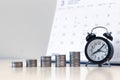 Alarm clock and money coins stack with calendar background, saving money Royalty Free Stock Photo