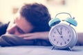 Alarm clock in the morning. Young man sleeps in the blurry background