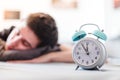 Alarm clock in the morning. Young man sleeps in the blurry background