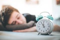 Alarm clock in the morning. Young man sleeps in the blurry background