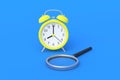 Alarm clock near magnifier on blue background