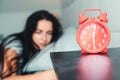 Alarm clock on nightstand. Asleep woman in early morning in bed. It is time to waking up. Red alarm clock. Young sleeping woman