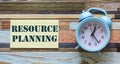 Alarm clock and note sticker on desk with text Resource planning. Royalty Free Stock Photo