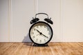 Alarm clock with 10 O`clock and twenty minuet, on wooden table and white wall Royalty Free Stock Photo
