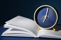 Alarm clock with open notebook on table against dark background. Time management concept Royalty Free Stock Photo