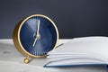 Alarm clock with open notebook on table against dark background. Time management concept Royalty Free Stock Photo