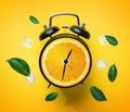 Alarm Clock of Orange Fruit Green Leaves and Ice Cube Flying Around on Yellow Background. Summer Concept Royalty Free Stock Photo