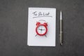 Alarm clock over spiral note pad with the to do list as a time management concept Royalty Free Stock Photo