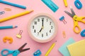 Alarm clock, paint, pencils and scissors. School accessories on a pink background. Back to school concept
