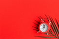 Alarm clock and palm leaf on bright red background. Royalty Free Stock Photo