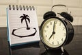 An alarm clock and a picture of the island on the Notepad sheet . Royalty Free Stock Photo