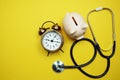 Alarm clock with piggy saving and stethoscope top view on yellow background Royalty Free Stock Photo