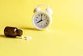 Alarm clock, pills, a jar of medicine on yellow background. Concept Insomnia, sleep problems, time to take pills