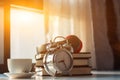 Alarm clocks and coffee mugs are placed on a wooden table by the window in the morning to prepare to work at home to help reduce t