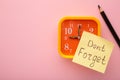 Alarm clock and reminder note with phrase Don`t forget on pink background Royalty Free Stock Photo