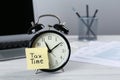 Alarm clock and reminder note with words Tax Time on white wooden table. Space for text Royalty Free Stock Photo